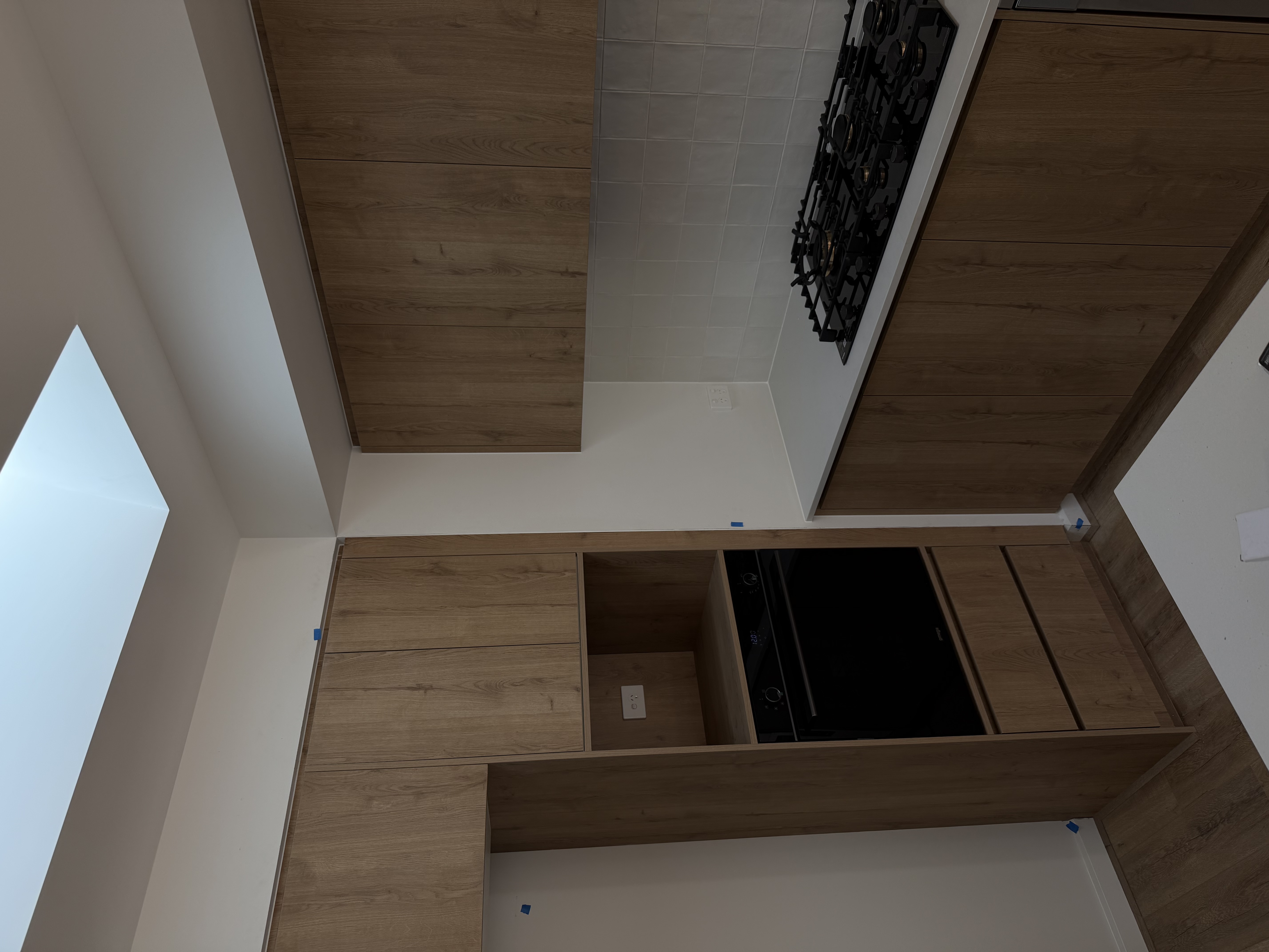 In-progress turnkey kitchen build — custom timber joinery, integrated oven and gas cooktop installed
